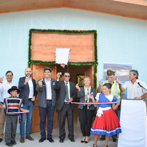 People at a ribbon-cutting ceremony in front of a building, holding pieces of ribbon and smiling.